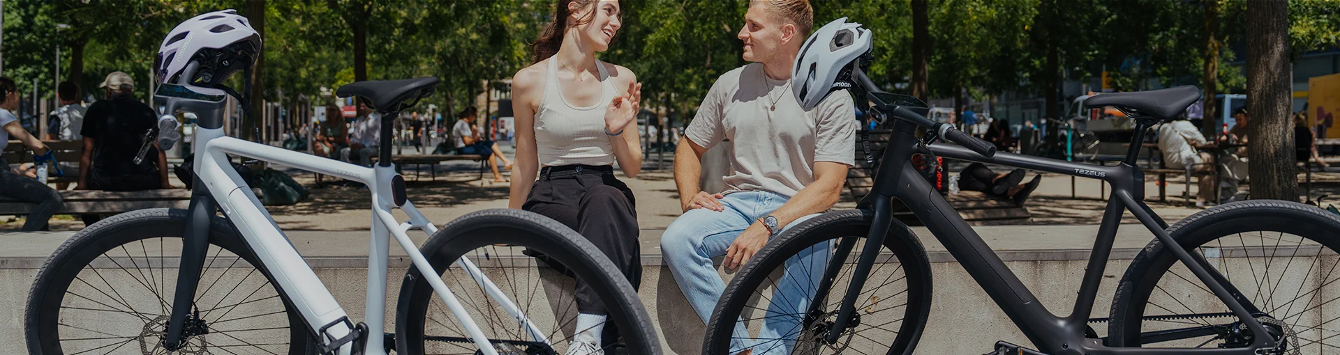 Two riders sitting between a white and black Tezeus e-bike